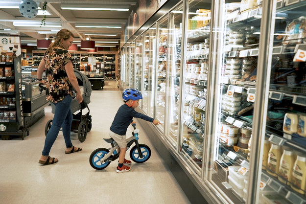 Mother with child in supermarket's cooling section