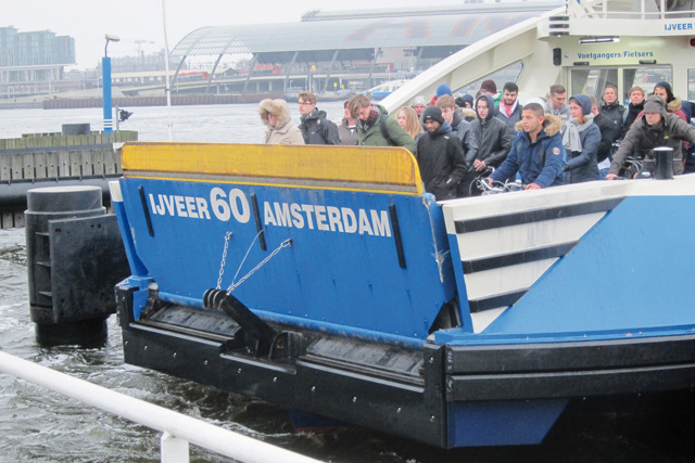 Hybrid ferry in Amsterdam full of passengers approaching the dock