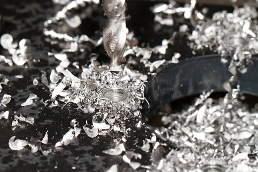 Tip of a drill surrounded by boron shavings