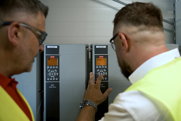 Two workers looking at the drives. One of them is pressing the buttons and setting it up. 
