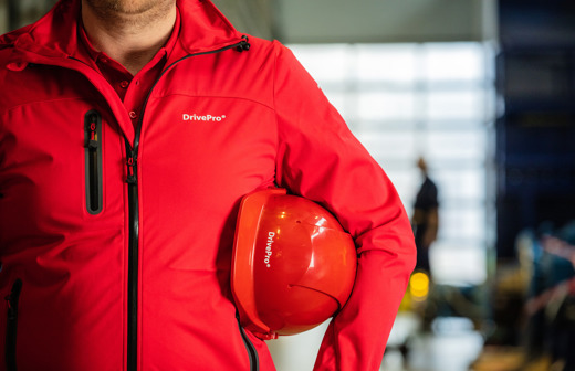 DrivePro man in a red DrivePro jacket with his helmet under his arm